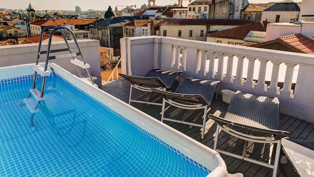 A rooftop pool with a view of the cityscape, including a church tower and residential buildings. - Rivoli Cinema Hostel (Porto)