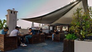 A rooftop terrace with wooden seating and planters, offering a view of the city skyline. - Rivoli Cinema Hostel (Porto)
