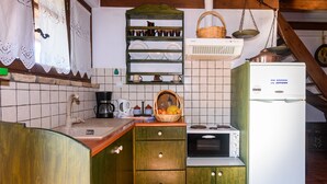 A kitchen with wooden cabinets, a white refrigerator, a stove, and a hanging shelf with dishes. - Eros Home, Panoramic Sea View, Perfect location (Pylos-Nestoras)