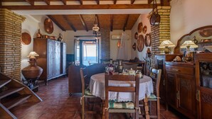 A rustic dining area with a wooden table, chairs, and a brick wall. - Eros Home, Panoramic Sea View, Perfect location (Pylos-Nestoras)