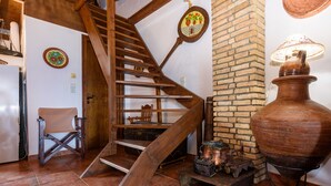 A rustic interior with a wooden staircase, a brick wall, a large clay pot, and a vintage lamp. - Eros Home, Panoramic Sea View, Perfect location (Pylos-Nestoras)