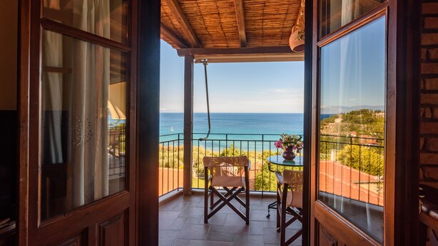 A balcony with a wooden ceiling, a table with chairs, and a view of the sea. - Eros Home, Panoramic Sea View, Perfect location (Pylos-Nestoras)