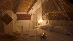 Una habitación con cama, mesita de noche, lámpara y mosquitero.