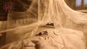 Una cama con dosel, una botella y vasos sobre la cama.