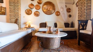 Una habitación acogedora con una mesa redonda de metal, una cama, una silla y una pared decorada con placas de cobre.