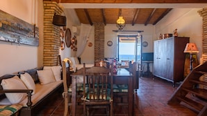 Un interior rústico con una mesa de comedor de madera, un sofá y una escalera.