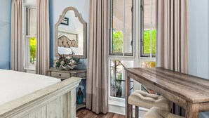 A bedroom with a bed, a dresser, a mirror, a window with curtains, and a wooden table. - Golf Cart ~ 2nd Floor Studio ~ Kitchenette (Miramar Beach)