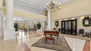A spacious lobby with a grand piano, a chandelier, and a high ceiling. - Golf Cart ~ 2nd Floor Studio ~ Kitchenette (Miramar Beach)