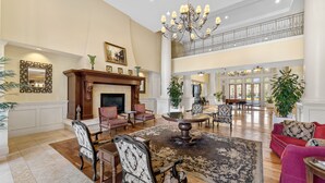 A spacious living room with a fireplace, multiple seating areas, and a chandelier. - Golf Cart ~ 2nd Floor Studio ~ Kitchenette (Miramar Beach)