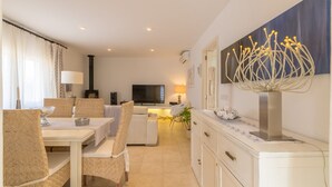 Una sala de estar moderna con comedor, televisor de pantalla plana y una escultura decorativa.
