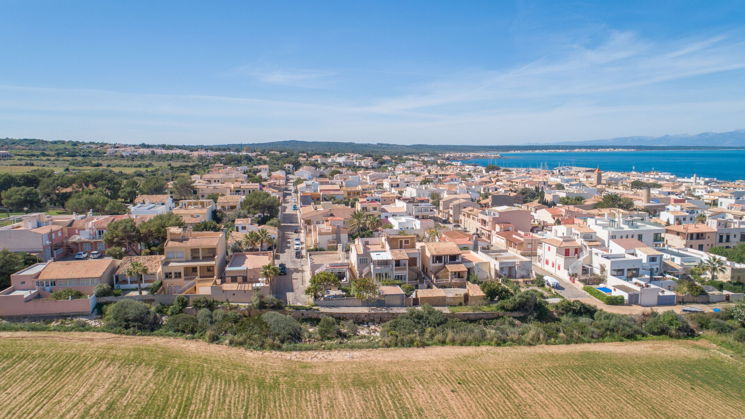 An aerial view of a coastal town with a mix of residential buildings, some with visible balconies and terraces.