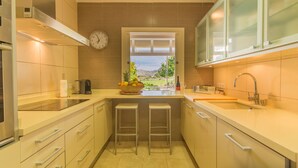 Una cocina moderna con un ventanal grande, un reloj y un frutero sobre la encimera.