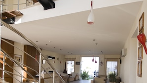 A spacious living area with a staircase, sofas, and potted plants.