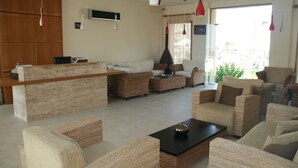 A spacious living area with wicker furniture, a black coffee table, and a TV mounted on the wall.