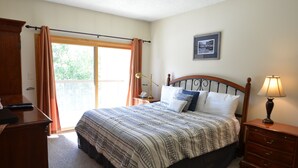 A bedroom with a bed, a nightstand, a dresser, a desk, and a window with curtains.