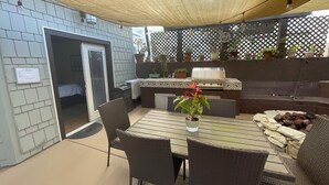Une terrasse extérieure avec une table et des chaises, un barbecue et des plantes en pot.