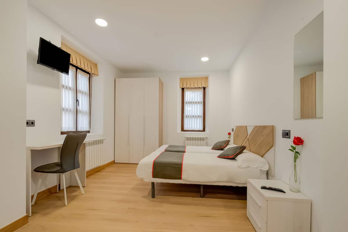 Un dormitori amb un llit, un escriptori i una cadira.