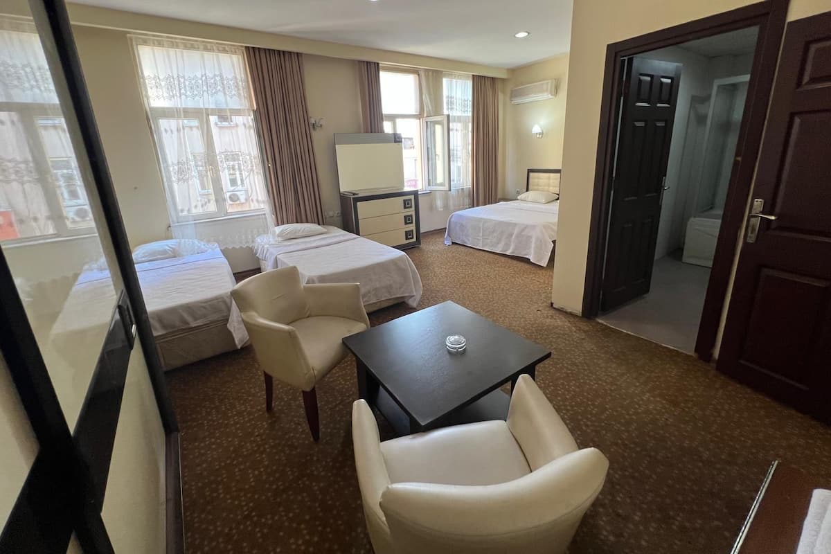 A hotel room with two beds, a desk, a chair, and a window.