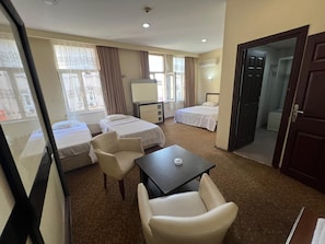A hotel room with two beds, a desk, a chair, and a window. - Grand Adanus Hotel (Adana)
