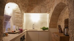 Une cuisine avec une arche en pierre, un évier, un grille-pain et un bloc à couteaux.