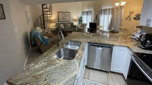 Uma cozinha moderna com bancadas de granito, eletrodomésticos de aço inoxidável e máquina de lavar louça embutida.