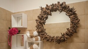 Ein Badezimmer mit Spiegel, weißen Regalen und einem dekorativen Holz-Kranz.