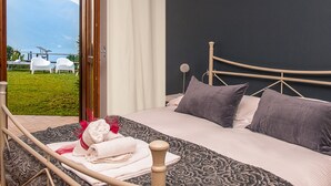 Ein Schlafzimmer mit Bett, Kissen und Blick auf eine Wiese und Berge.