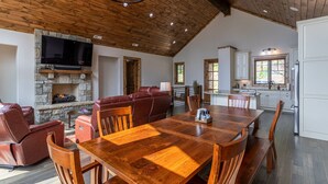 A spacious living area with a stone fireplace, leather seating, and a wooden dining table. - Clouds Rest- luxury pet friendly home in Eagles Nest with hot tub, year round views, and more (Banner Elk)