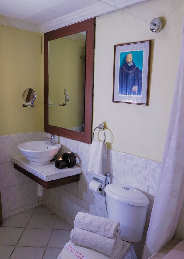 A bathroom with a sink, mirror, toilet, and a framed picture on the wall. - Sprout Rooms (Quezon City)