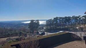 A view of a coastal area with a clear sky, a body of water, and a hilly landscape with trees and a building. - Dimora Miralago -  with panoramic view of the lake (San Zeno Di Montagna)