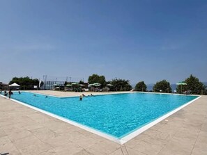 Una piscina rectangular con agua azul cristalina, rodeada por una solana con baldosas.