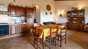 A kitchen with wooden cabinets, a dining table with chairs, and a tiled floor. - Dimora Miralago -  with panoramic view of the lake (San Zeno Di Montagna)