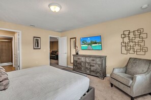 Ein Schlafzimmer mit einem Bett, einem Fernseher, einem Schminktisch und einem Sessel.