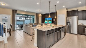 Een moderne keuken met een centraal eiland, roestvrijstalen apparatuur en hanglampen.