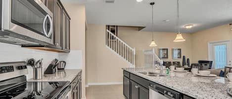 A kitchen with stainless steel appliances, granite countertops, and pendant lighting.