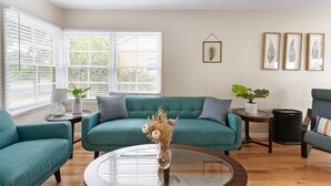 Ein Wohnzimmer mit Türkis-Sofas, einem Glastisch und einer Topfpflanze.