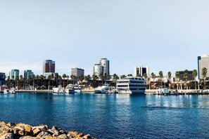 Ein Yachthafen mit mehreren dort liegenden Yachten, ein Stadtpanorama im Hintergrund und eine felsige Küstenlinie im Vordergrund.