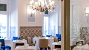 A restaurant interior with tables set for dining, a chandelier, and patterned wall tiles. - Casa de Sao Mamede Hotel (Lisbon)