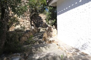 A stone pathway leading to a white building, surrounded by trees and a stone wall. - Aria di Vacanza - Costa Dorata Cod 4 (Loiri Porto San Paolo)