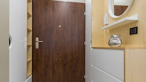 A hallway with a wooden door, a mirror, and a shelf with a decorative owl. - P&O Apartments Cybernetyki 6 (Warsaw)