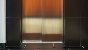 An elevator with metallic doors and a control panel on the left. - P&O Apartments Cybernetyki 6 (Warsaw)