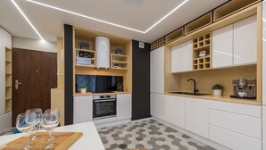 A modern kitchen with white cabinets, a built-in oven, and a wooden countertop. - P&O Apartments Cybernetyki 6 (Warsaw)