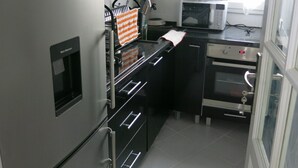 A compact kitchen with a refrigerator, oven, microwave, and a small sink. - Building part of the city's heritage (Joinville-le-Pont)