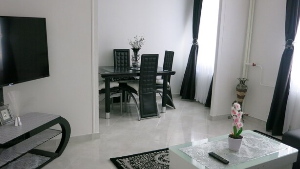 A modern living room with a flat-screen TV, a glass coffee table, a sofa, and a dining area with a table and chairs. - Building part of the city's heritage (Joinville-le-Pont)