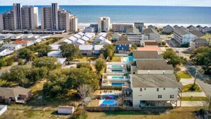 A coastal residential area with a variety of houses, some with swimming pools, and a beachfront view.