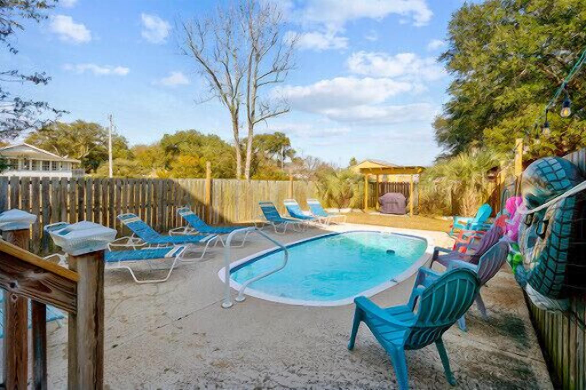 Ein Garten mit Swimmingpool, blauen Liegestühlen und einer Holzterrasse.