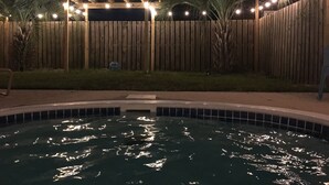 A swimming pool with a wooden fence and palm trees in the background.
