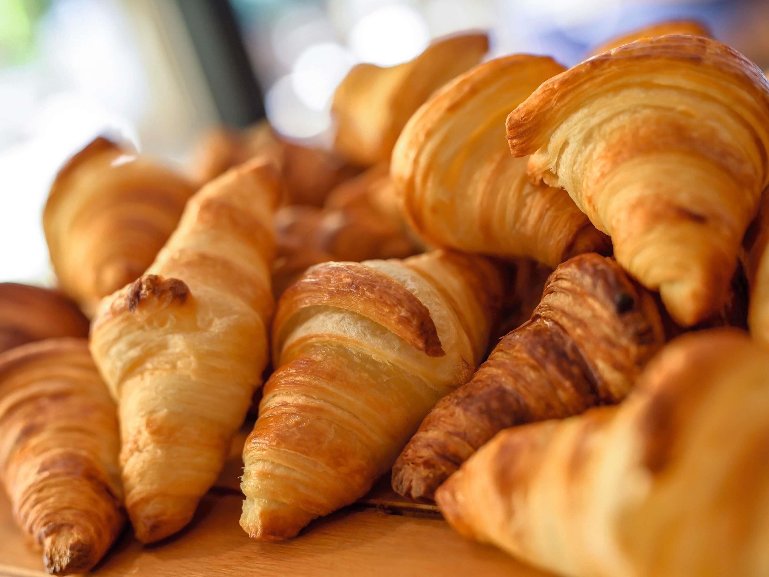 A collection of golden-brown croissants arranged on a wooden surface.