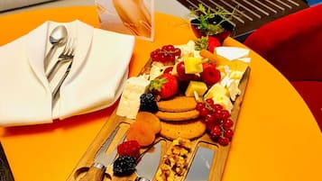 Pöydällä on juustolajitelma, hedelmiä, pähkinöitä ja ruokailuvälineitä.