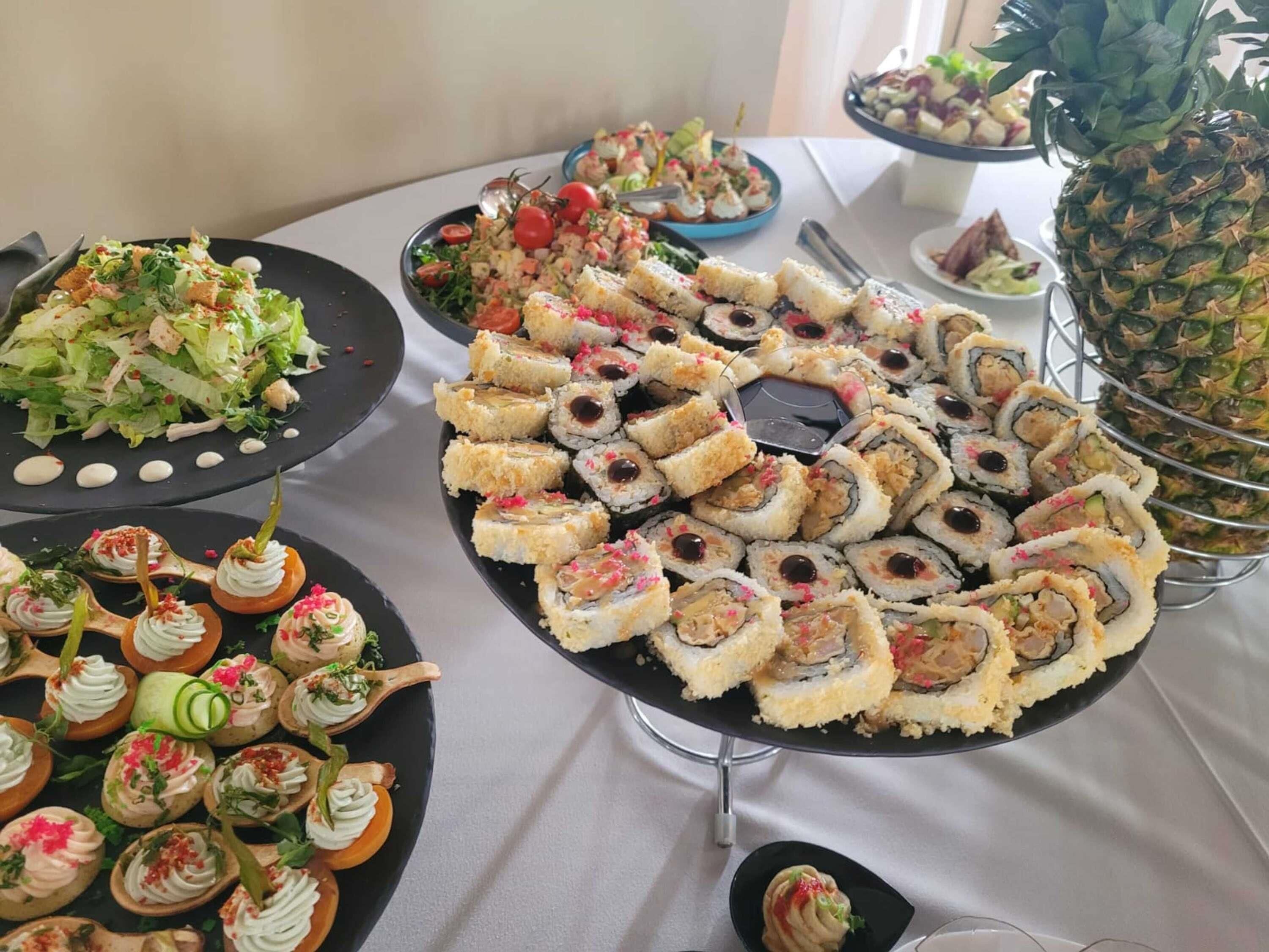 A buffet table with various food items including sushi, salads, and appetizers.